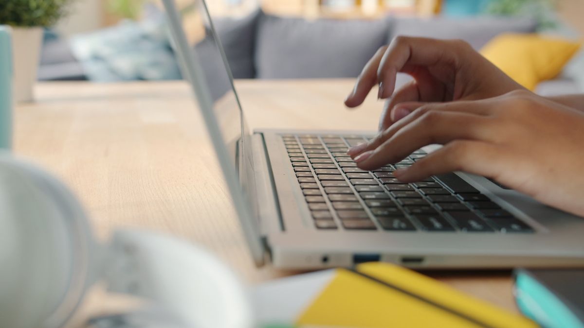 Hender som skriver pa et laptop-tastatur ved et skrivebord