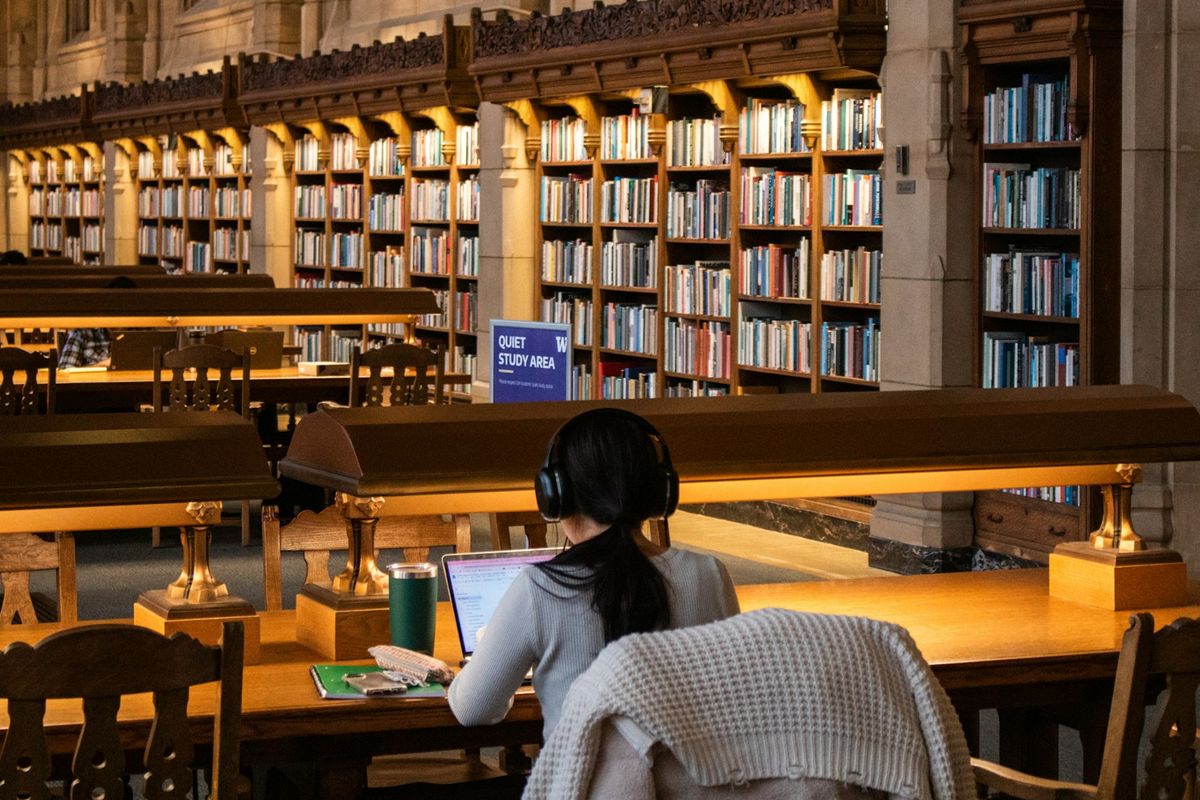 Voksen student studerer med bøker på bibliotek