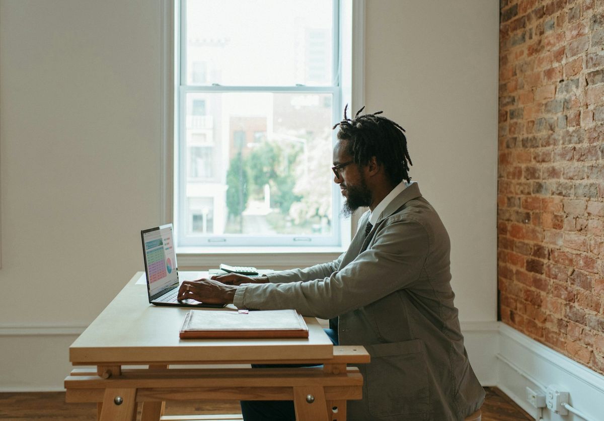 Person ved skrivebord med laptop og papirer